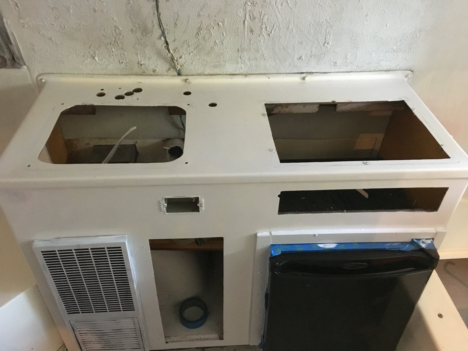 Here the kitchen unit is nearly completely stripped down, with the original sink and stove gone. You can also see where I filled in some more holes on the front. I didn't need to fill the ones on top because I was building a new countertop. 